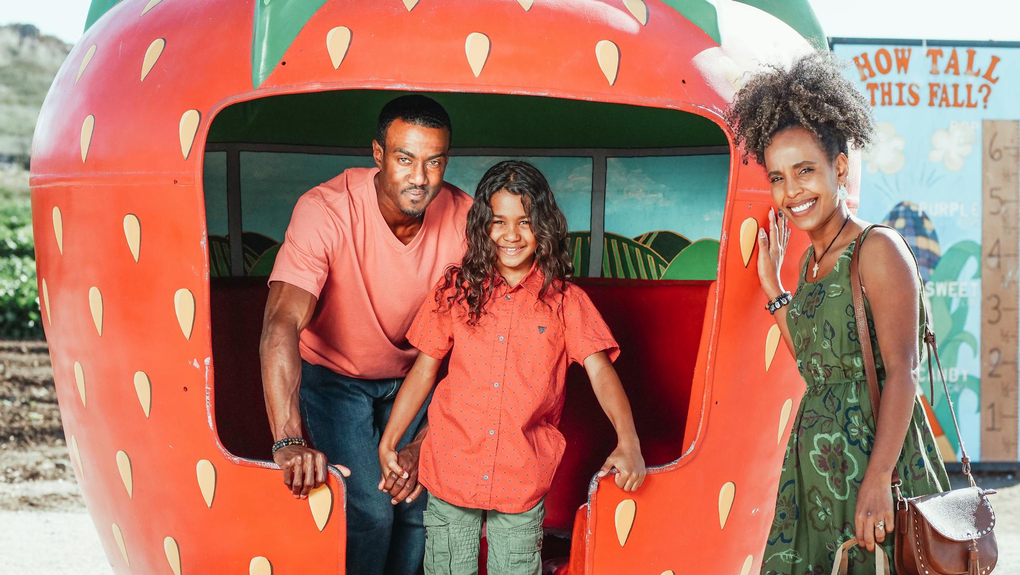 A joyful family enjoying a day out at the strawberry farm in summer.